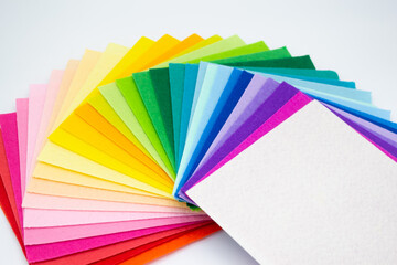 The square pieces of felt spread out by a color spectrum on similarity of a rainbow: from shades of red, pink, yellow, green, blue and bright white at the end. Copy space