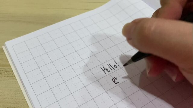 Korean Studying Hand Writing. Writing Hello with brush pen in Hangul Korean alphabet.