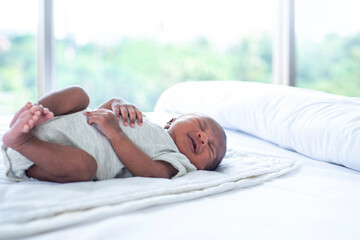Obraz na płótnie Canvas Dark skinned new born baby boy relax in a white bedroom, 15 days year old, newborn at home