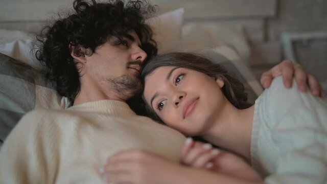 Close-up of young romantic cute couple lying in bed wearing winter clothes