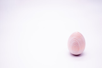 One unpainted hand-made wooden egg on a white background. Copy space