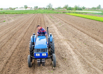 Obraz premium A farmer on a tractor carries out land work by milling and grinding the soil and removing roots after last harvest. Loosening surface, cultivation. Farming, agriculture. Use of agricultural machinery