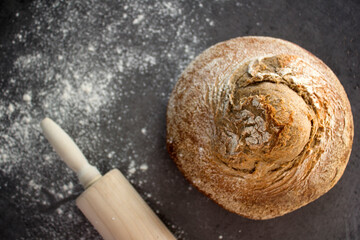 Fresh baked round bread made of whole wheat.  Dark grey background with copy space. Top view photo of homemade bread.