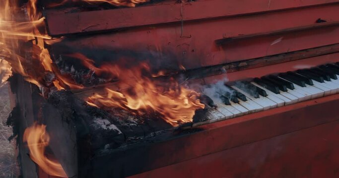 Close up pano of burning orange piano in a autumn field during a snowfall. Flames and smoke around. The art concept scene.