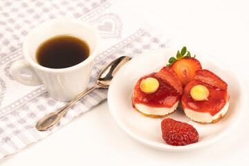 white cup expresso of coffee with strawberries and purple flowers on a table ready for breakfast italian pastries