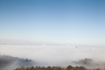 Roofs of several high rise building in the fog with blue sky