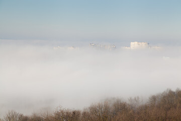 Fototapeta na wymiar Roofs of buildings in the fog with blue sky