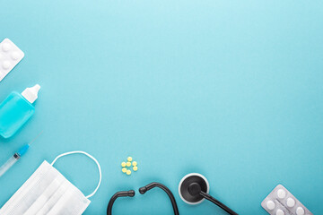stethoscope, mask, syringe, antiseptic, pills on a blue surface