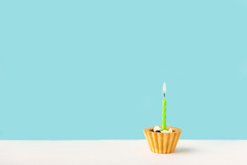 one cupcake with a candle on a white wooden surface