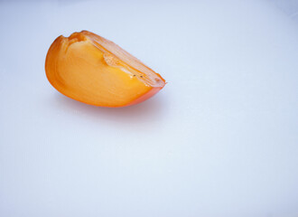 Fresh ripe persimmons with slices of persimmon on a plate with cutlery and whole fruit on gray stone background. Space for text. Close-up photo. Concept of health fruit.