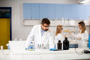 Researcher in white lab coat  working using laptop while sitting in the laboratory