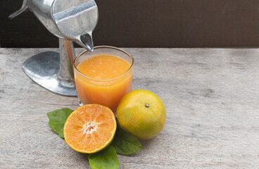 Orange juice in glass and fresh citrus around with Juicer hand press squeezer fruit on wood table. 