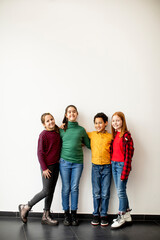 Obraz premium Portrait of cute little kids in jeans looking at camera and smiling, standing against white wall