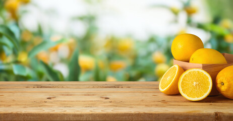 Oranges fruit on wooden table over blurred green tree background