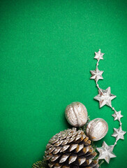 Fototapeta na wymiar New Year's green background with pine cone, stars and silver nuts.