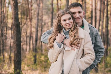 
the guy hugs the girl and smiles in the pine forest