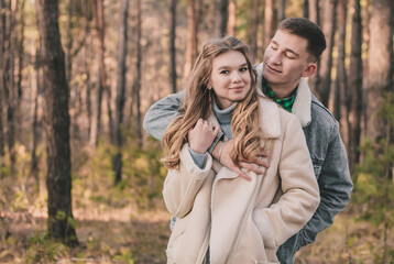 
the guy hugs the girl and smiles in the pine forest