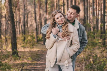 Fototapeta premium the guy hugs the girl and smiles in the pine forest