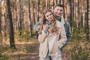 
the guy hugs the girl and smiles in the pine forest
