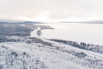 Fototapeta na wymiar Stunning winter aerial view, drone of Yukon Territory in northern Canada. Taken in December cold, freezing season with wilderness woods and huge frozen lake. 