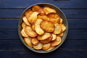 Homemade organic beautiful salted potato chips fried in oil in a plate Top view