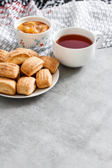 Tasty breakfast. Homemade sweet cinnamon cookies and cup of tea. Apple confiture on background