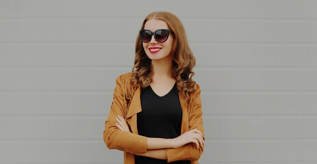 Portrait of beautiful young woman wearing a brown jacket on a gray background