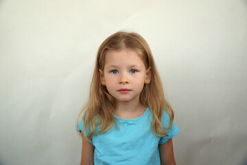 Naklejka premium Cute little girl shows emotions on a white background in a T-shirt. Simple beauty. High quality photo