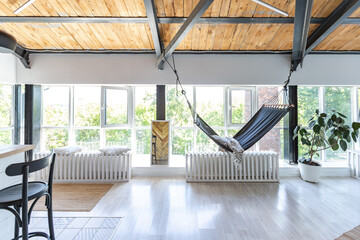 stylish kitchen interior design. white walls and wooden decoration. beautiful hammock and high windows.