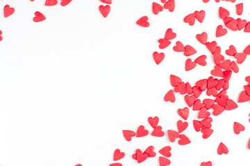 Red confectionery confetti in the shape of hearts on a white background copy space.