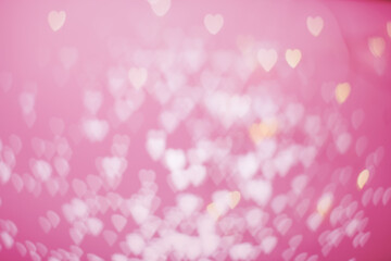 Yellow and pink bokeh in the shape of hearts on a pink background copy space. Valentine background