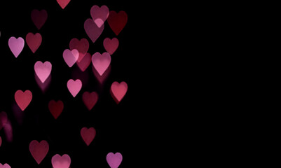 Yellow and pink bokeh in the shape of hearts on a black background copy space. Valentine background