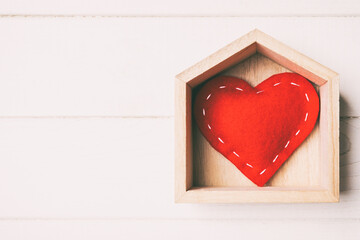 Top view of red textile heart in a house on wooden background. Home sweet home concept. Valentine's day