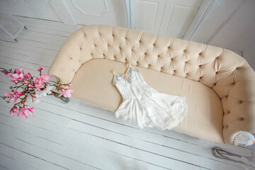 White ballerina dress lies on a beige sofa in the dance hall