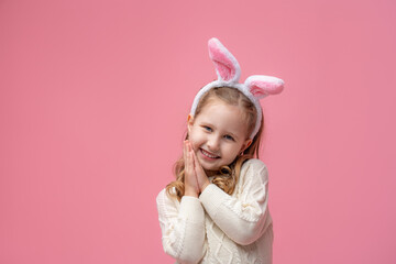Obraz na płótnie Canvas cute little girl with bunny ears on a pink background.
