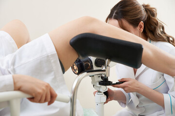 Gynecologist examining a patient with a microscope in modern medical clinic
