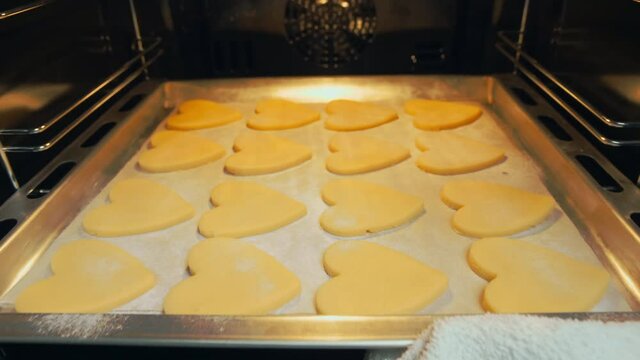 Baking sweet valentines. Gift for Valentine's Day and International Women's Day. Put a baking sheet with cookies in the oven to bake