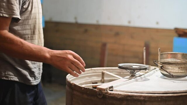 Beekeeper is filling up a honey extractor with a honeycomb and spinning uncapped frames in the centrifuge metal container, the process of honey extraction.