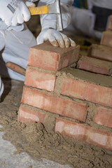 Bricklayer Builds Brick Wall With Small Bricks And Masonry Hammer - Close-up
