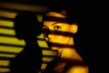 sunset light falling through the blinds on the face of beautiful girl