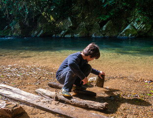 Boy playing with stone next to the river in rain forest