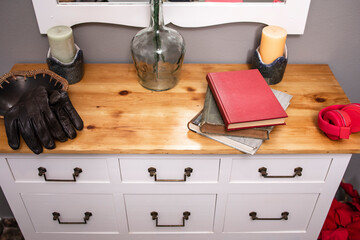 Books, headphones and leather gloves on hall furniture.