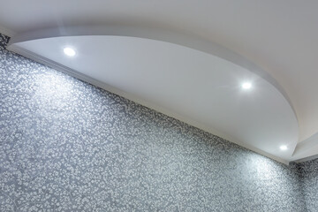 Detail of corner ceiling with intricate crown molding. Suspended ceiling and drywall construction in empty room in apartment or house. Stretch ceiling white and complex shape.