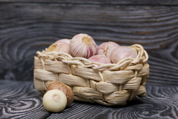 Garlic in a wicker basket. On black pine boards. Close-up shot.