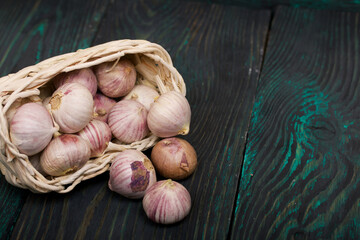Garlic in an overturned wicker basket. On green pine boards. Close-up shot.