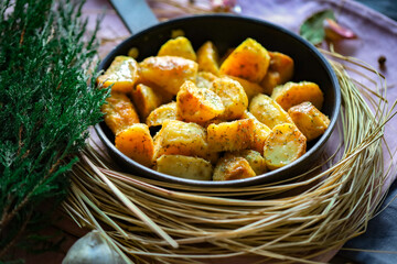 Przypieczone smaczne ziemniaki na patelni z ziołami. Fotografia kulinarna, tło naturalne, wiejski klimat