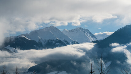 beautiful view to the snow capped mountains and alps on a foggy and sunny winter day