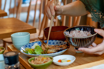 焼き魚定食を食べている、箸を持った女性の手元