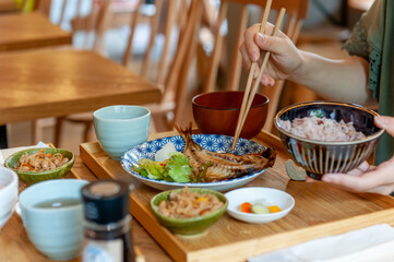 焼き魚定食を食べている、箸を持った女性の手元