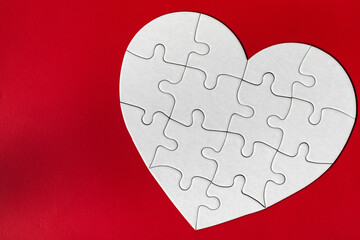 Obraz na płótnie Canvas Heart-shaped jigsaw puzzle on color background. Puzzle heart on wooden background. A missing piece of the heart puzzle. Heart shape jigsaw puzzle. Puzzles in the shape of a heart.